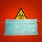 Door sign of biohazard, dangerous contamination as viral, bacterial or fungi, and a medical face mask, details, closeup