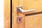 Door to a darkened room open a little, metal handle with a key hole closeup, inside shot, modern interior house wooden door gap