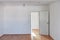 Door and wall in empty room with hardwood parquet