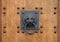 Doorknocker in the shape of a lion head holding a ring on the wooden gate