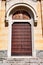 The doors to the divine temple, brown with patterns in a white opening, under a fresco depicting saints.