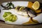 Dorada fish cooked in the oven with lemon, pimento and green onion served on a tray on a wooden table