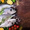Dorada, fresh fish with vegetable, lemon, herbs, onion, paprika, cherry tomatoes, onion, salton dark vintage background. Copy spac