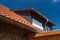 Dormer window with blinds, ceramic tiles visible, against the blue sky.