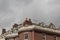 Dormers and chimney pipes along the top of old brownstone apartment buildings, grey skies