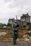 Dornie, Scotland; August 27th 2019: A Scottish bagpiper playing his musical instrument above Eilean Donan Castle