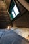 Double bed in bedroom of pyramid shape wooden cabin. Pyramid shape walls of bungalow from inside. Small room, angled walls, window