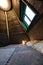Double bed in bedroom of pyramid shape wooden cabin. Pyramid shape walls of bungalow from inside. Small room, angled walls, window