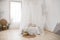 Double bed with gray bed linen and canopy. Bedroom. A wicker chair made of wood in the corner of the room.