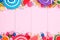 Double border of assorted colorful candies against pink wood