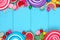 Double border of colorful assorted candies against blue wood