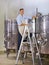 Double checking is key. Portrait of a mature wine maker standing next to his steel vats in his cellar.