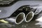 Double chrome exhaust pipe of powerful sport car with grey plastic details