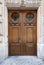 Double door entrance of historic building in Paris France. Vintage wooden doorway and stone fretwork decorations of stone wall.