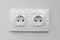 Double electrical socket on white wallpaper