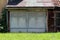 Double elongated large old vintage retro garage doors with blue metal frame and dirty grey panels mounted on wooden garage