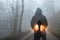 A double exposure concept. A hooded figure looking at a silhouette of a man in front of car headlights. On a spooky forest track o