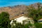 Double gable style roof on modern house or home with orange adobe tiles and white stucco exterior in sunlight