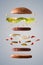 Double hamburger floating with lettuce onion and pickles gray background