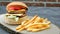 Double juicy cheeseburger with french fries, lettuce, tomato, cheddar cheese front of vintage brick wall