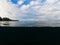 Double landscape with sea and sky. Above and below waterline in tropical seashore. Dark seawater and sunny sky.