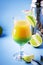 Double layer green yellow alcoholic cocktail with mango juice, rum, liqueur, lime and ice, blue background, copy cpase