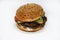 Double meat burger with vegetables on a white background. Delicious cheeseburger on a plate. Meat fast food. A large hamburger