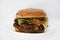 Double meat burger with vegetables on a white background. Delicious cheeseburger on a plate. Meat fast food. A large hamburger