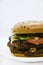 Double meat burger with vegetables on a white background. Delicious cheeseburger on a plate. Meat fast food. A large hamburger