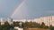 Double Multicolored Bright Rainbow in Sky above Roofs Modern Buildings in Town