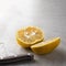 Double organic lemon cut into two pieces with seeds unusual shape and knife on grey background with copy space. Buying
