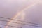 Double rainbow behind rows of a barbed wire