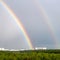 Double rainbow over forest and city in spring