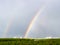 Double rainbow over green city park and houses