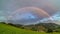 Double Rainbow over Green Meadow and Rural Landscape with Cloudy Sky Time Lapse