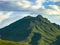 Double top mountain with green slopes against a cloudy backdrop on a summer day. Eagle Mountain, East Kazakhstan, Altai Mountains