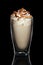 Double walled glass with coffee cocktail decorated with whipped cream and nuts isolated on black