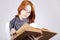 Doubting girl in glasses with old book