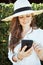 Doubting modern woman in white shirt using smartphone app