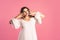 Doubting plus size model in white dress on pink background