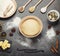 Dough in bowl, butter on slate plate, flour, eggs and spices, on gray surface