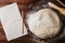 Dough with flour, baking paper, rolling pin, wheat ears on rustic table top view. Homemade pastry for bread or pizza.