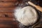 Dough with flour, rolling pin, wheat ears on rustic wooden table from above. Homemade pastry for bread or pizza. Bakery background