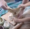 Dough in the hands of a man and a little girl, on a wooden table and a green towel.