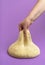 Dough isolated on a purple table. Woman stretching uncooked dough