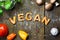 Dough letters and vegetables on rustic wooden table, word vegan