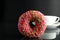 Doughnut with pink icing berliner lies next to a cup of coffee tea delicious breakfast snack day without diet on black background