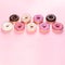 Doughnuts with multicolored glaze laid out on pink background. Square photo. Copy space