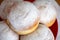 Doughnuts powdered with white ground sugar on a plate. Tasty homemade food close up view