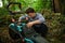 Down syndrome adult man emptying grass box in lawn mower outdoors in backyard.